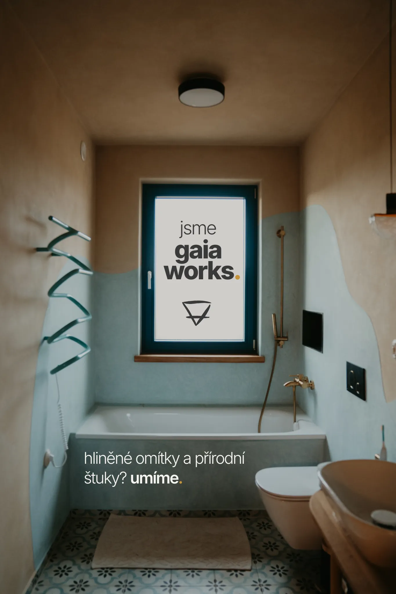 Koupelna z tadelaktu s prosvětleným oknem, v okně nápis Jsme GAIA WORKS a symbol země, na vaně nápis Hliněné omítky a přírodní štuky v současné architektuře? Umíme.